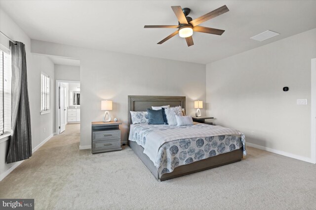 bedroom with ceiling fan, connected bathroom, and light colored carpet