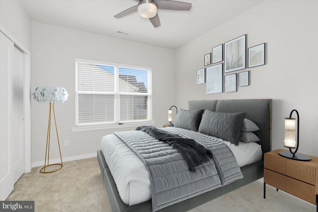 bedroom featuring ceiling fan, light colored carpet, and a closet