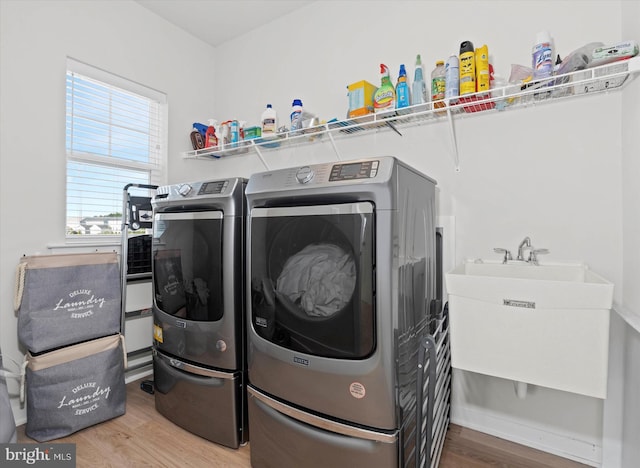 clothes washing area featuring washer and dryer, sink, and light hardwood / wood-style flooring