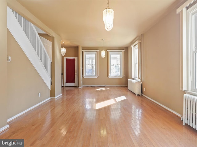 entrance foyer featuring a notable chandelier, radiator heating unit, and light wood-type flooring