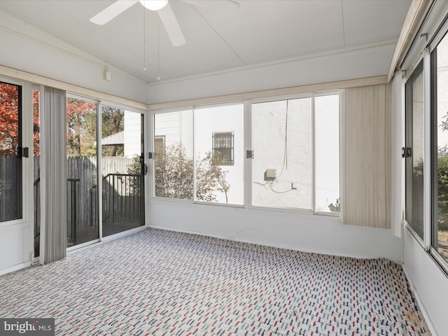 unfurnished sunroom with ceiling fan, vaulted ceiling, and a wealth of natural light