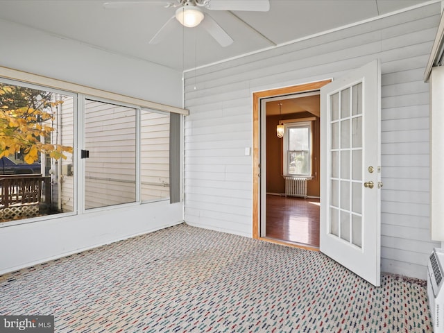 unfurnished sunroom with ceiling fan and radiator