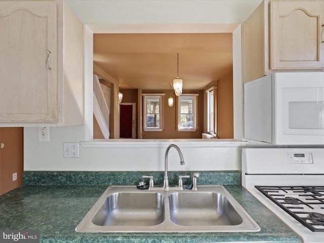 kitchen with sink, light brown cabinets, hanging light fixtures, and white appliances