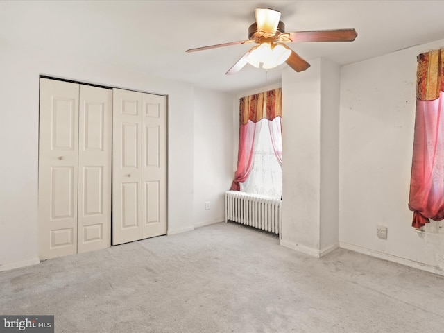 unfurnished bedroom with radiator, ceiling fan, a closet, and light colored carpet