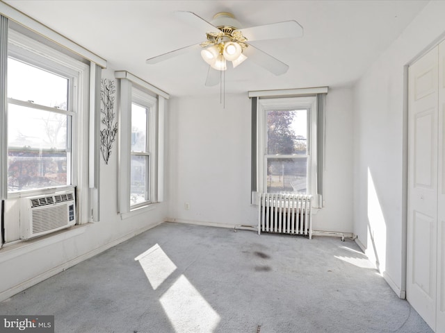 spare room with light colored carpet, radiator, and ceiling fan