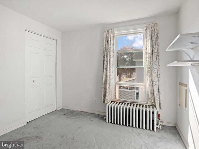 unfurnished bedroom with light carpet, cooling unit, a closet, and radiator