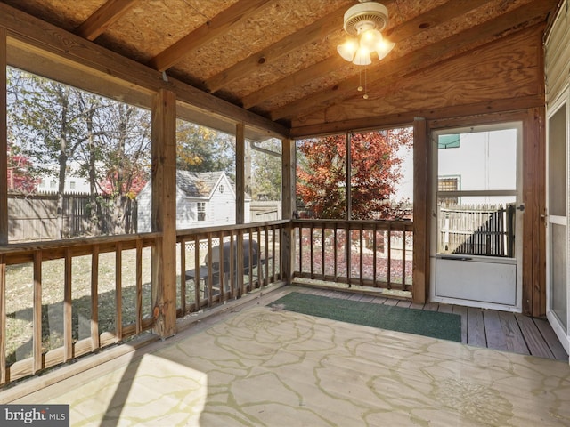 unfurnished sunroom featuring ceiling fan and vaulted ceiling with beams