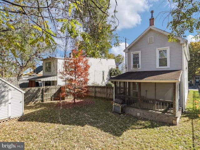 rear view of property featuring a lawn and a sunroom