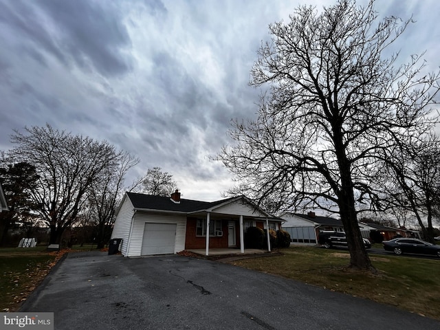 view of front of property featuring an attached garage, driveway, and a chimney