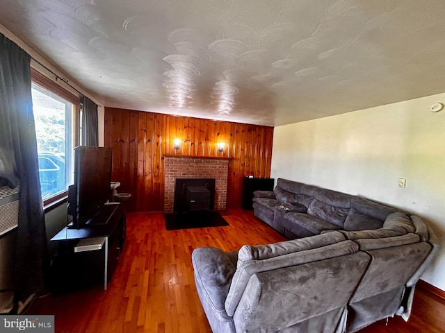 living area featuring a brick fireplace, wooden walls, and dark wood-style flooring