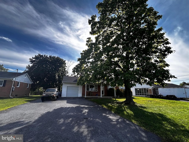 view of front of property featuring a garage, driveway, a front lawn, and brick siding