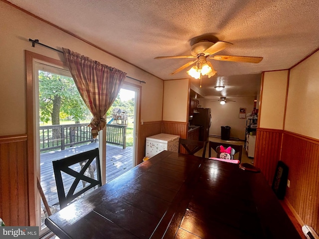 dining area with wainscoting, wood walls, and a textured ceiling