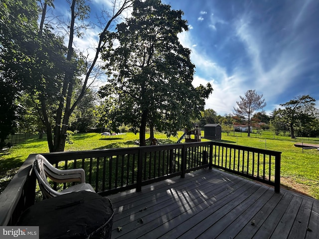 wooden deck featuring fence, a storage unit, an outbuilding, and a yard