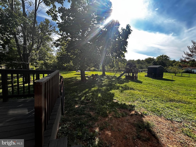 view of yard with a storage unit, a deck, a playground, and an outdoor structure