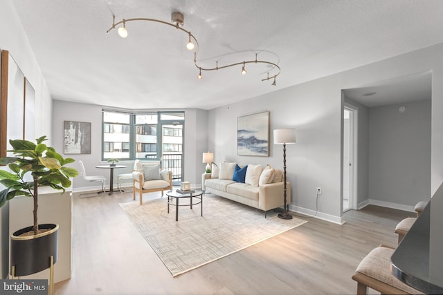 living area featuring a textured ceiling, baseboards, and wood finished floors