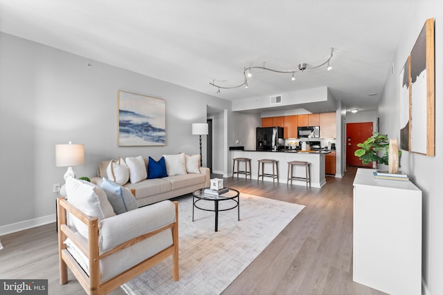 living room featuring rail lighting and light hardwood / wood-style floors