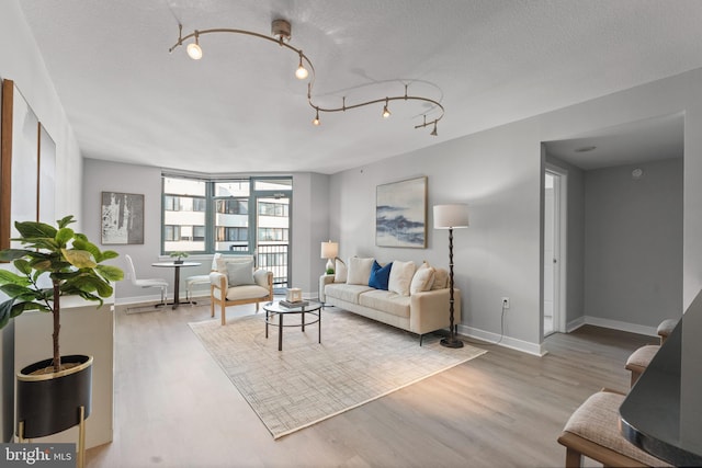 living room with a textured ceiling, rail lighting, and light hardwood / wood-style floors