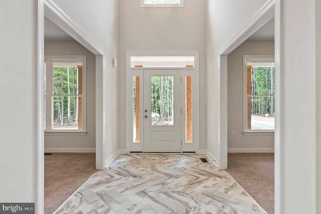 carpeted entryway with a towering ceiling and baseboards