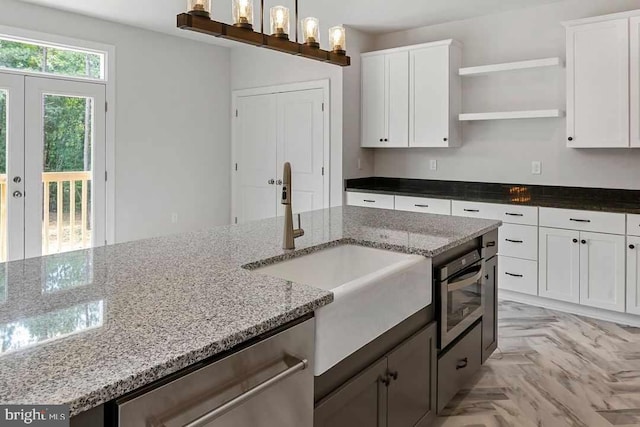 kitchen with light stone countertops, pendant lighting, light parquet floors, and white cabinetry