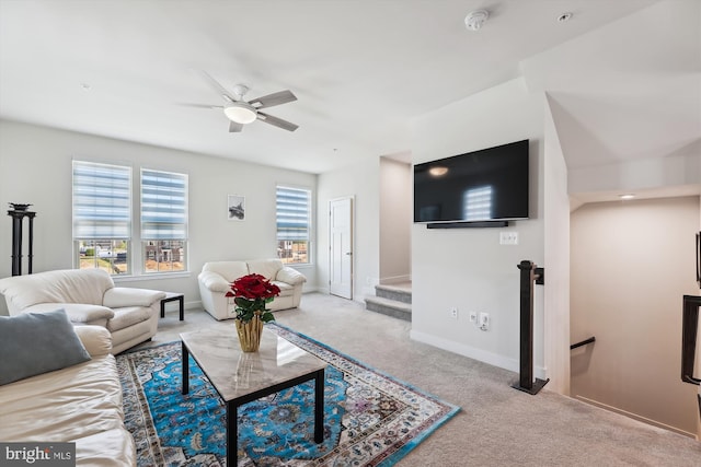 living area with baseboards, a ceiling fan, and light colored carpet