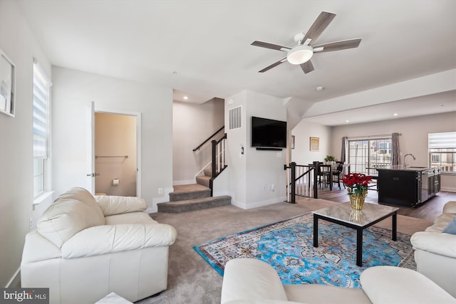 carpeted living room featuring ceiling fan and sink