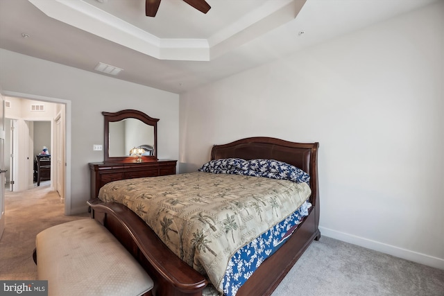 bedroom featuring ceiling fan, light carpet, and a tray ceiling