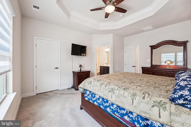 bedroom featuring a tray ceiling, ceiling fan, connected bathroom, and multiple windows