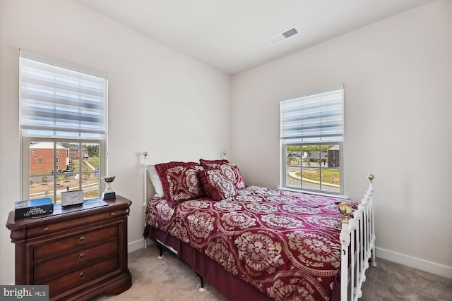 bedroom with multiple windows, visible vents, and light colored carpet