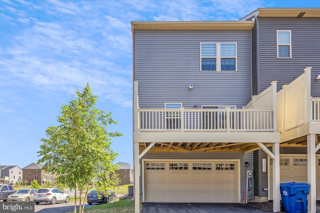 rear view of property featuring driveway, a balcony, and an attached garage