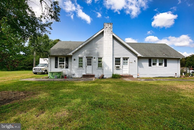 back of property featuring entry steps, roof with shingles, a lawn, and a chimney