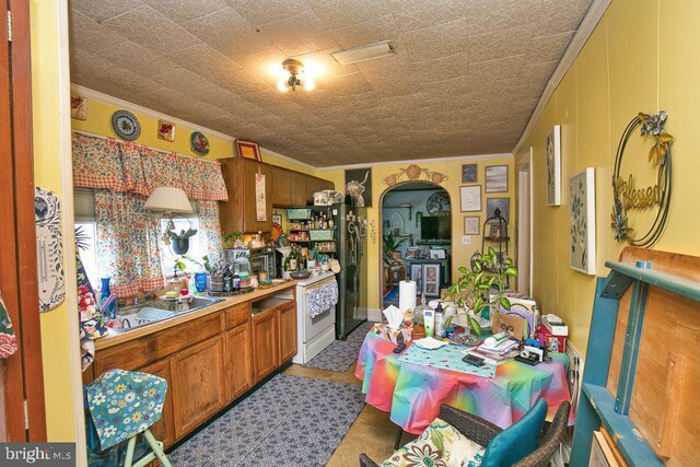 kitchen with light tile patterned floors, crown molding, and sink