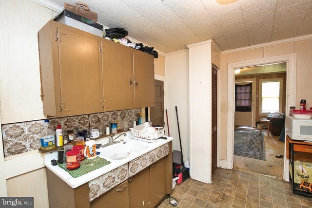 kitchen featuring backsplash, crown molding, and sink