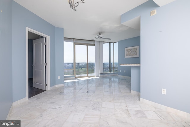 unfurnished room featuring ceiling fan, expansive windows, and light tile patterned floors