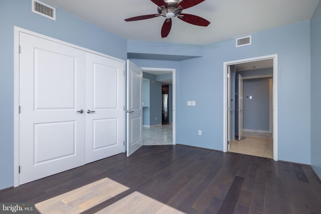 unfurnished bedroom with ceiling fan, a closet, visible vents, and dark wood-type flooring