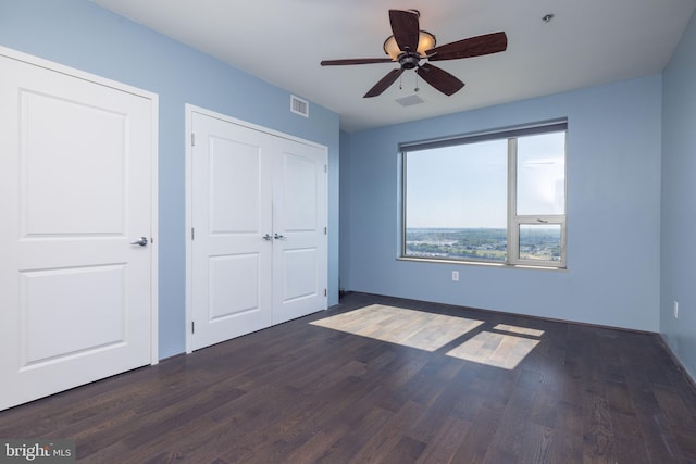 unfurnished bedroom with ceiling fan and dark wood-type flooring