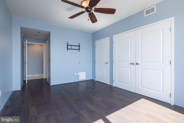 unfurnished bedroom featuring dark wood-style floors, a closet, visible vents, ceiling fan, and baseboards