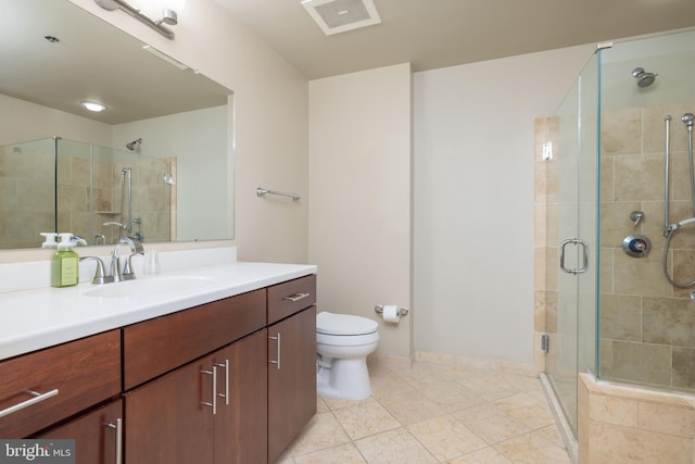 bathroom featuring tile patterned flooring, toilet, vanity, and a shower with shower door