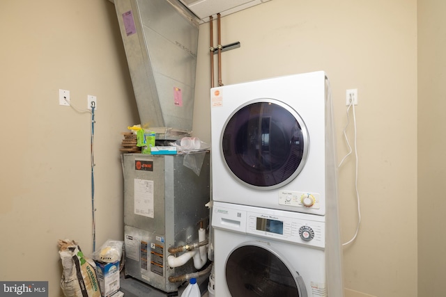 clothes washing area with stacked washing maching and dryer