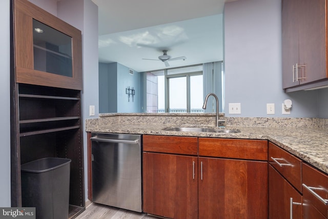 kitchen featuring ceiling fan, light wood-type flooring, stainless steel dishwasher, light stone countertops, and sink