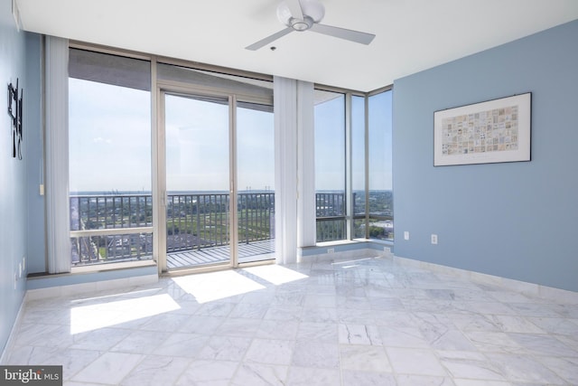 tiled empty room featuring ceiling fan and floor to ceiling windows