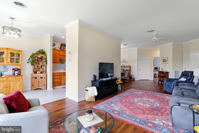 living room with crown molding, ceiling fan, and wood-type flooring