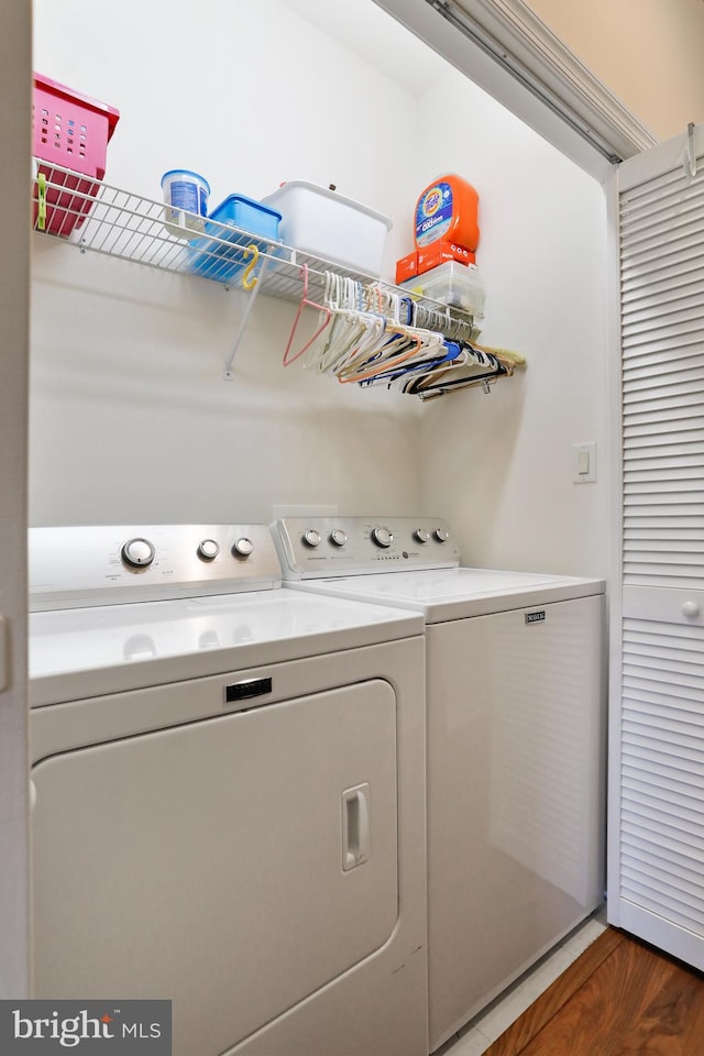 washroom with dark hardwood / wood-style flooring and washing machine and dryer