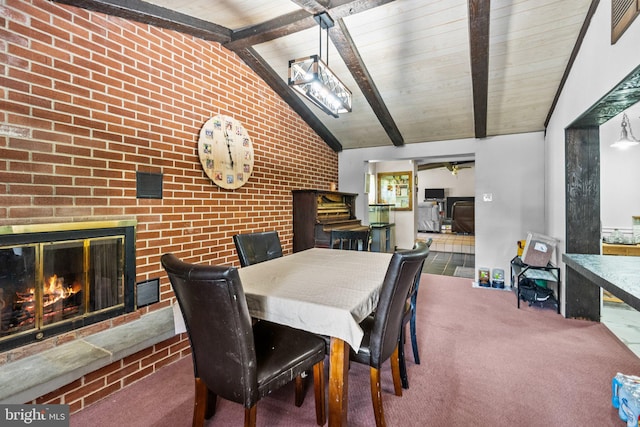 dining space featuring vaulted ceiling with beams, a fireplace, carpet, and wood ceiling