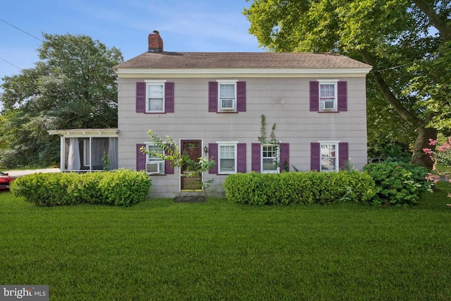 colonial house featuring a chimney, a front lawn, and cooling unit