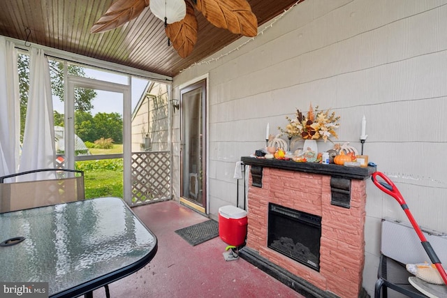 sunroom / solarium featuring ceiling fan and a fireplace