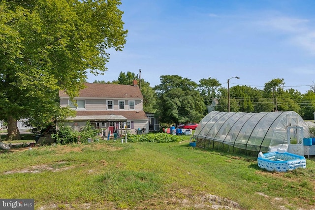 view of yard featuring a greenhouse and an outdoor structure