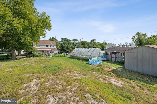 view of yard featuring a greenhouse and an outbuilding