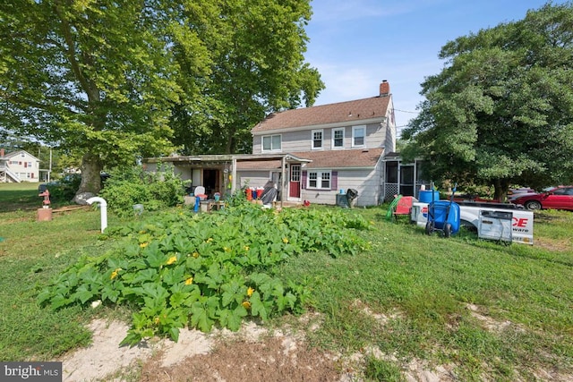 rear view of property featuring a chimney and a lawn