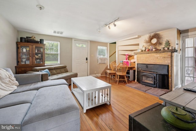 living room with a wealth of natural light, visible vents, stairway, and wood finished floors