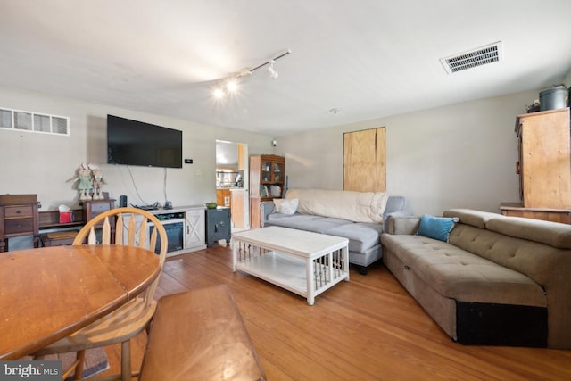 living area with rail lighting, visible vents, and light wood-style floors